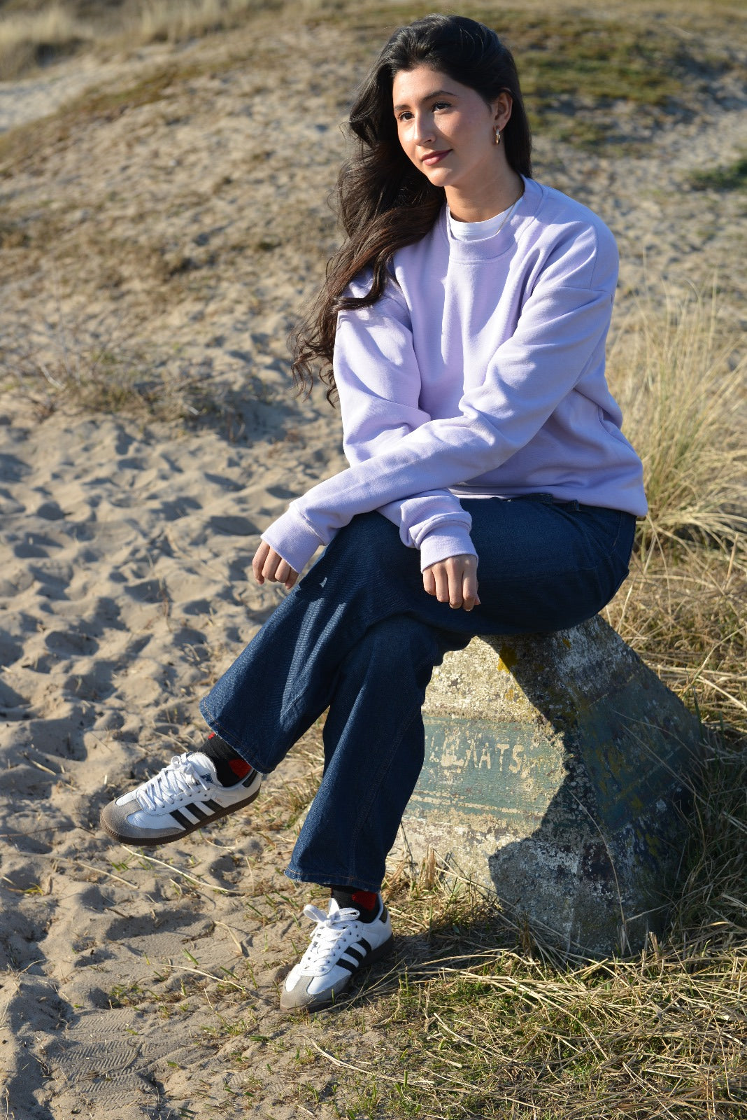 Model showcasing stylish lila crewneck sweater, combining comfort and fashion in a relaxed outdoor setting.