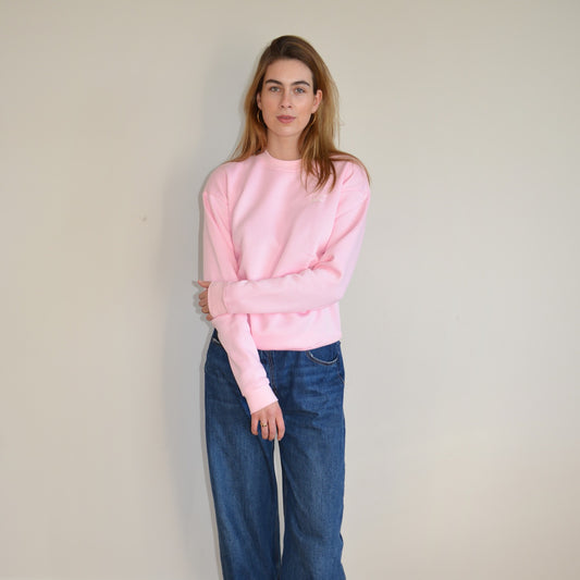 Young woman wearing a pink essential crewneck sweater, showcasing cozy and stylish casual wear.