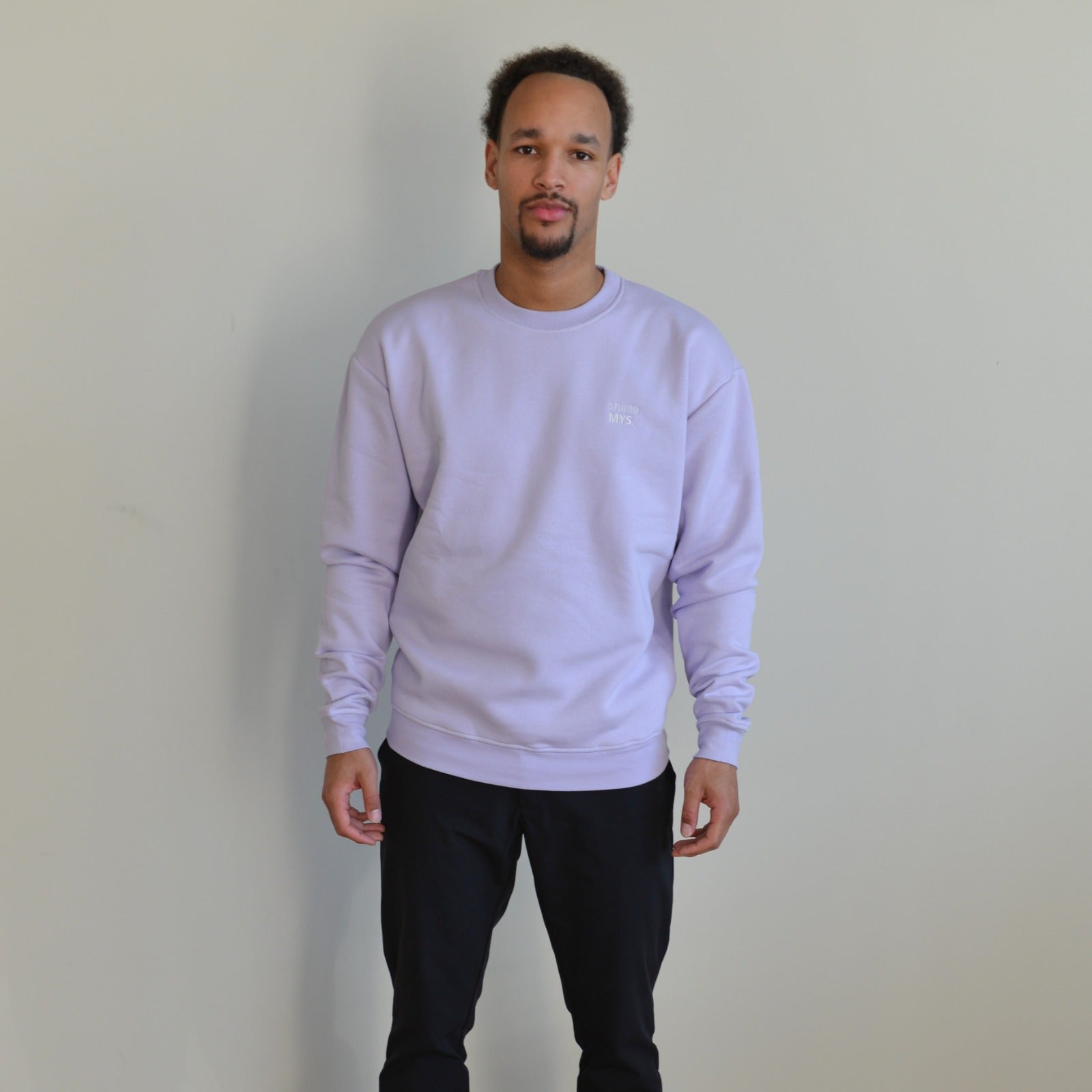 Stylish man wearing a lila crewneck sweater, blending comfort with a relaxed fit for every occasion.